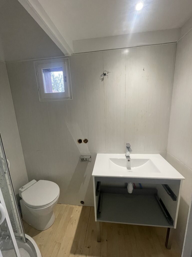 Salle de bain avant rénovation avec murs en PVC vieillissant et difficiles à nettoyer